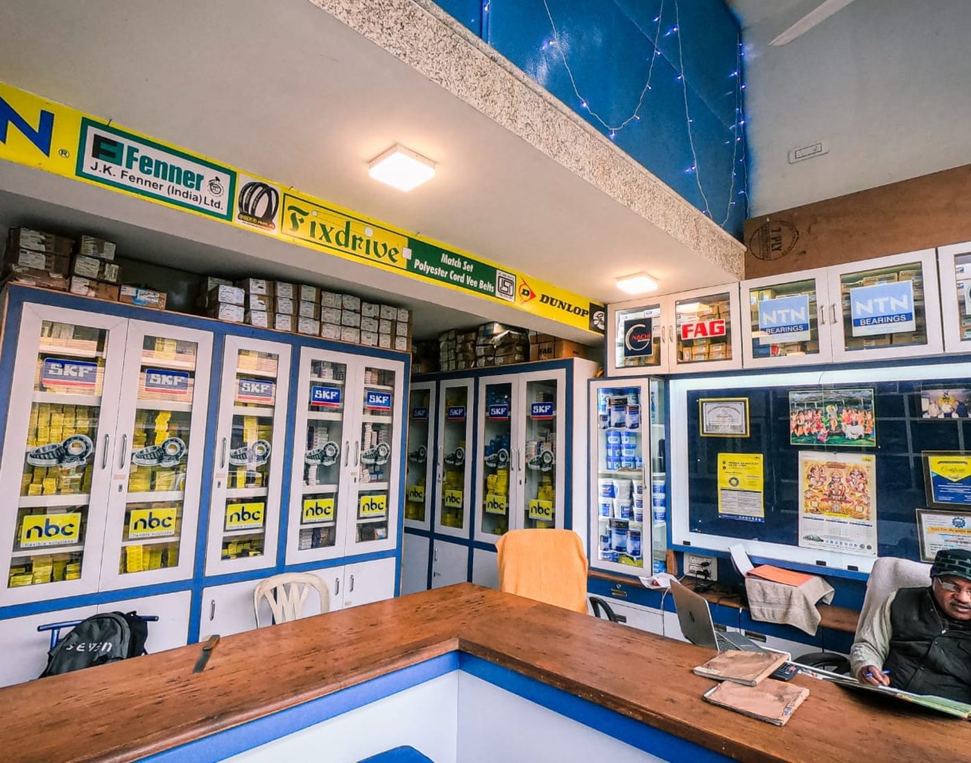 Inside Padam Chand Bearing & Belts showing JK Fenner authorized banner and Fixdrive Match Set polyester cord vee belts banner with full bearing inventory